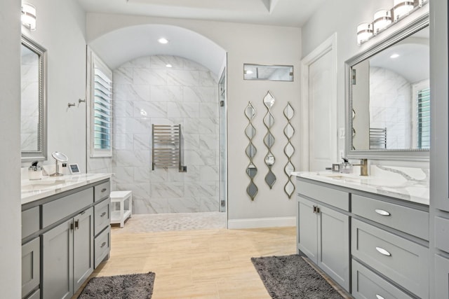 bathroom featuring two vanities, baseboards, a sink, and a walk in shower