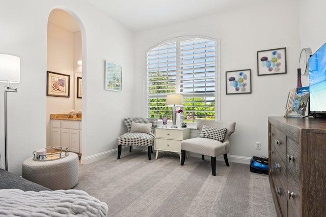 living area with arched walkways, carpet floors, and baseboards