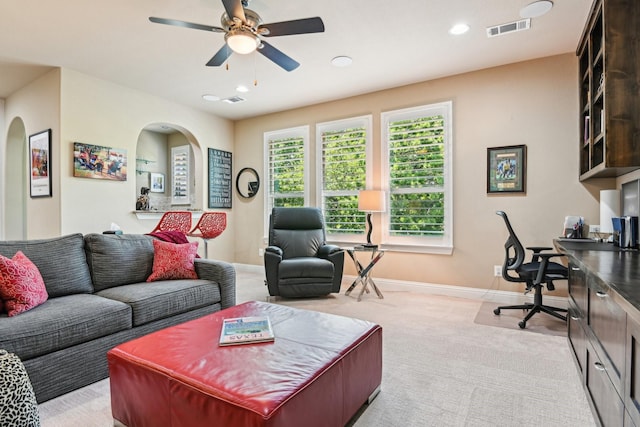 living area with a ceiling fan, arched walkways, light colored carpet, baseboards, and visible vents