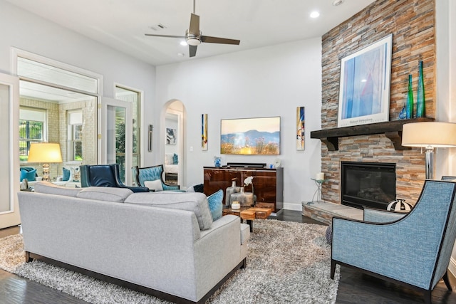 living area with wood finished floors, ceiling fan, arched walkways, a fireplace, and recessed lighting