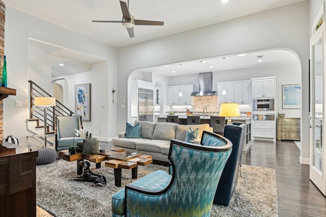 living room with a ceiling fan, arched walkways, recessed lighting, and dark wood finished floors