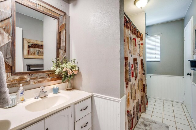 full bath featuring tile patterned floors, vanity, a shower with shower curtain, and wainscoting