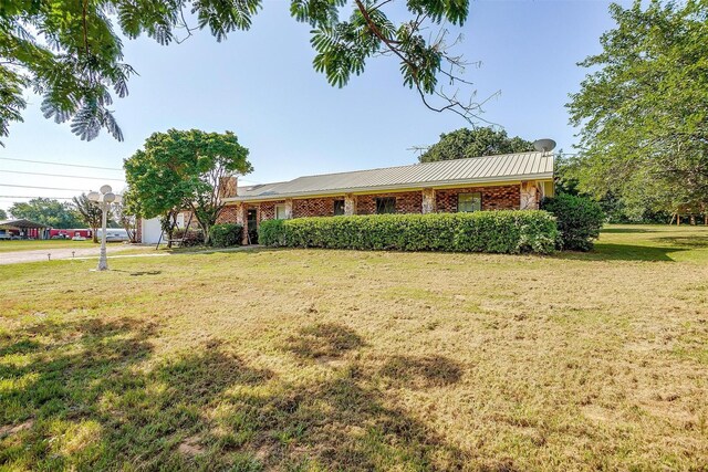 single story home featuring metal roof and a front yard