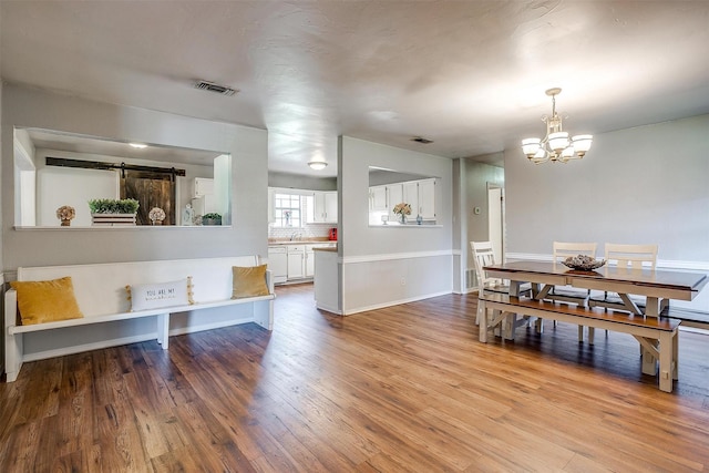 dining space featuring visible vents, baseboards, a chandelier, and wood finished floors