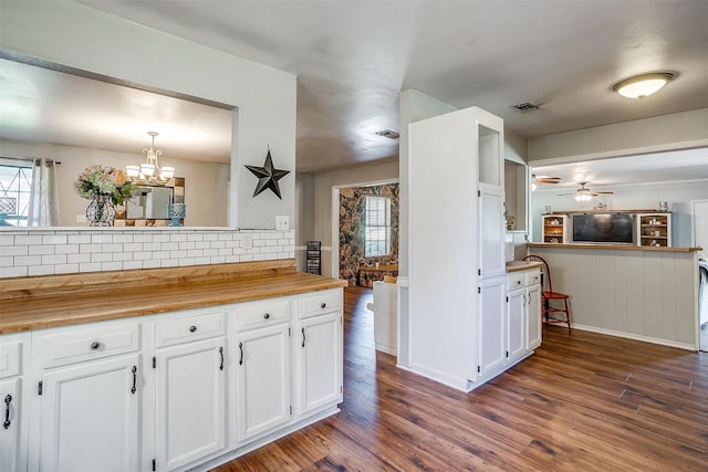 kitchen with tasteful backsplash, visible vents, white cabinetry, and dark wood finished floors