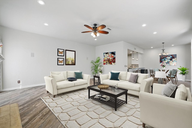 living area featuring ceiling fan with notable chandelier, visible vents, recessed lighting, wood finished floors, and baseboards