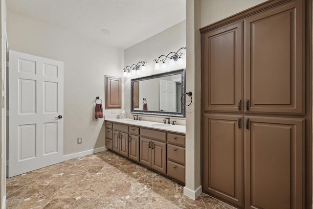 bathroom featuring double vanity, baseboards, and a sink