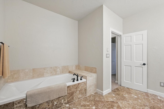 full bathroom with a bath and baseboards