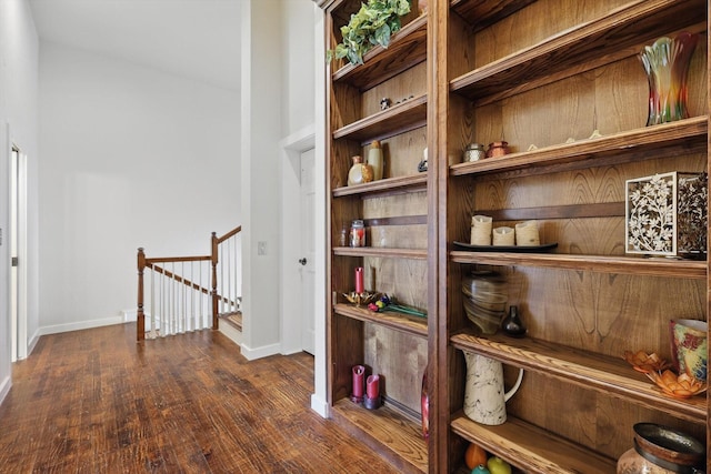 hall with wood finished floors, baseboards, and an upstairs landing