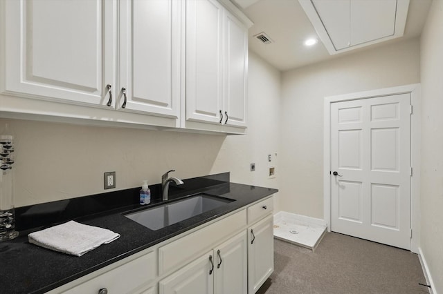laundry room with baseboards, a sink, carpet, attic access, and cabinet space