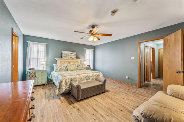 bedroom with light wood-style flooring, a ceiling fan, and multiple windows