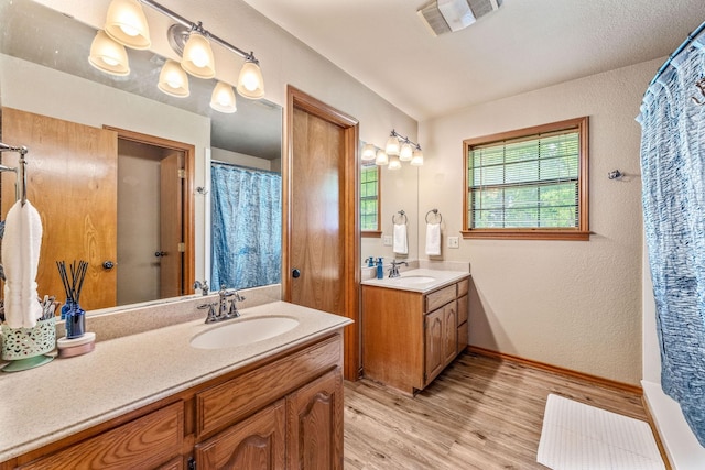 bathroom featuring a sink, visible vents, two vanities, and wood finished floors