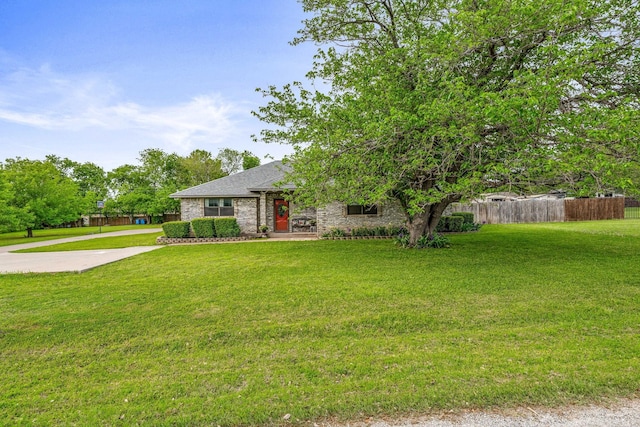 view of property hidden behind natural elements with a front yard, fence, and roof with shingles