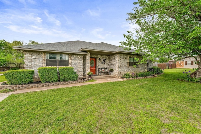 view of front facade featuring a front yard, fence, and brick siding