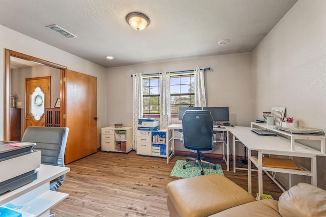 home office with visible vents, wood finished floors, and a textured ceiling