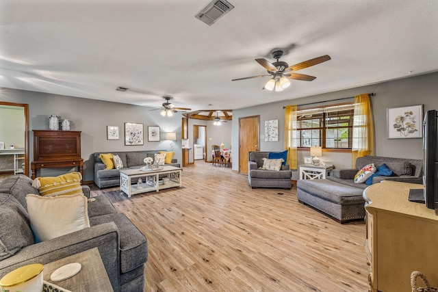 living area featuring light wood-style flooring, visible vents, and ceiling fan