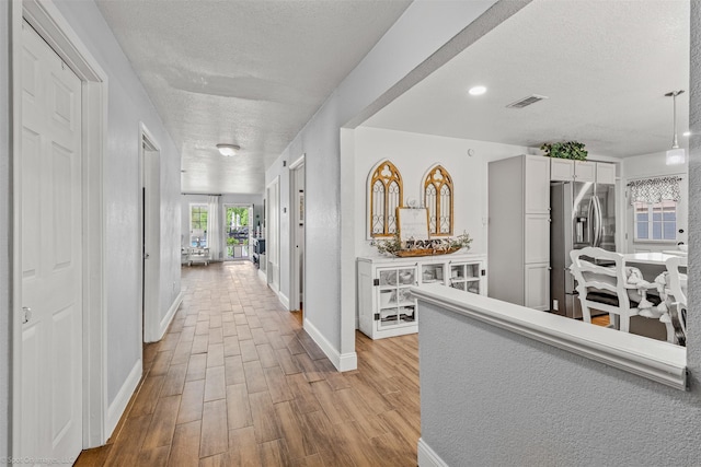868 Briggs Blvd, East Tawakoni, TX 75472 - hall with light wood finished floors, visible vents, a textured ceiling, and baseboards