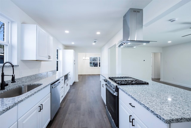 kitchen with a sink, island exhaust hood, dark wood finished floors, stainless steel appliances, and light stone counters