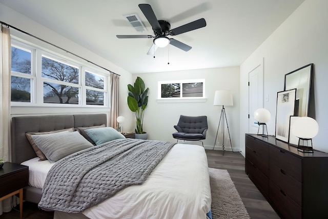 bedroom featuring ceiling fan, visible vents, baseboards, and dark wood finished floors