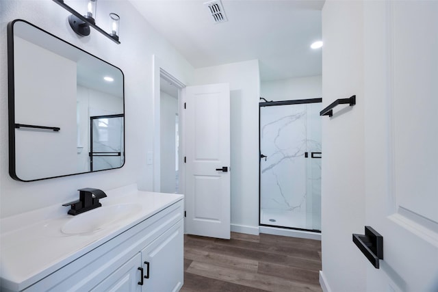 full bathroom featuring vanity, visible vents, a marble finish shower, and wood finished floors