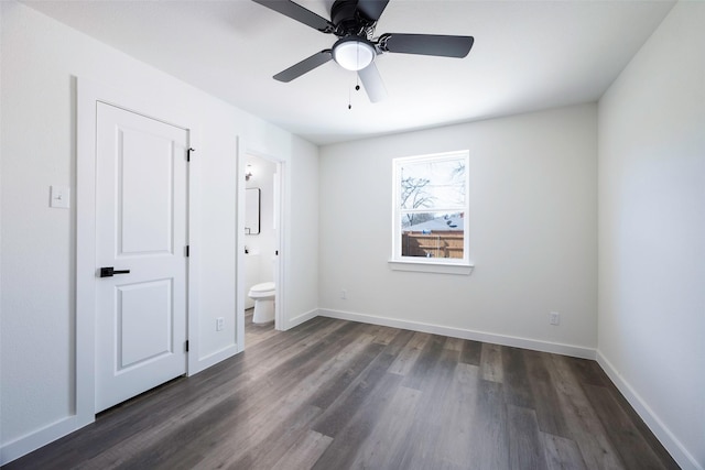 unfurnished bedroom with baseboards, a ceiling fan, ensuite bath, and dark wood-style floors