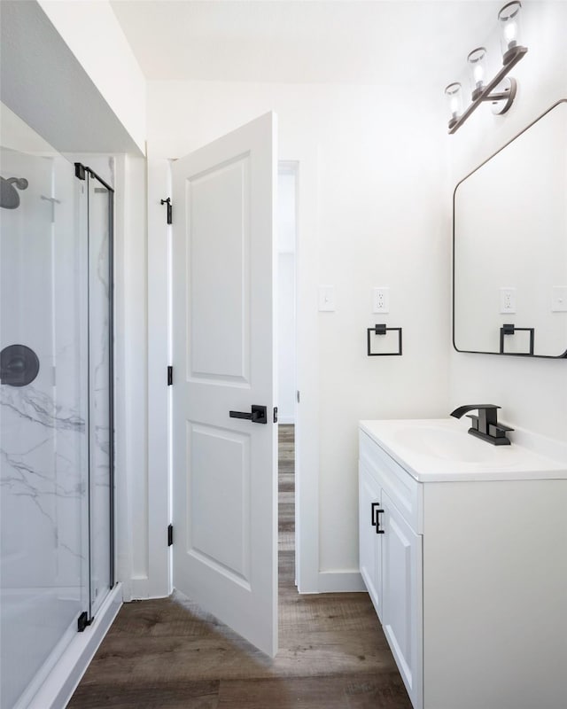 bathroom with vanity, a marble finish shower, and wood finished floors