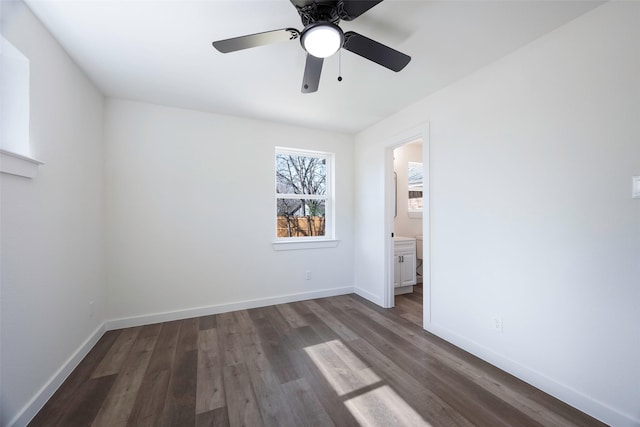 unfurnished bedroom with baseboards, connected bathroom, ceiling fan, and dark wood-style floors
