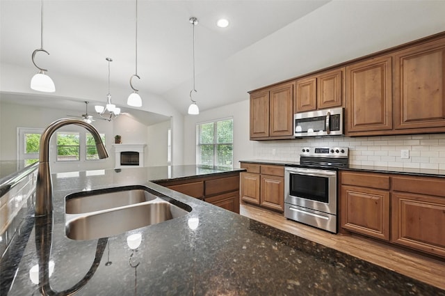 512 Hidden Springs Trl, Azle, TX 76020 - kitchen with stainless steel appliances, brown cabinetry, a sink, decorative light fixtures, and tasteful backsplash