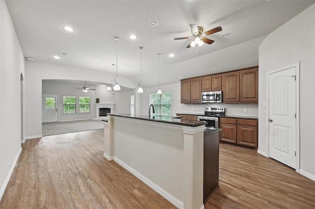 512 Hidden Springs Trl, Azle, TX 76020 - kitchen featuring stainless steel appliances, ceiling fan, a fireplace, open floor plan, and plenty of natural light