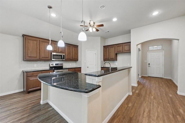 512 Hidden Springs Trl, Azle, TX 76020 - kitchen featuring stainless steel appliances, arched walkways, dark wood-type flooring, tasteful backsplash, and ceiling fan