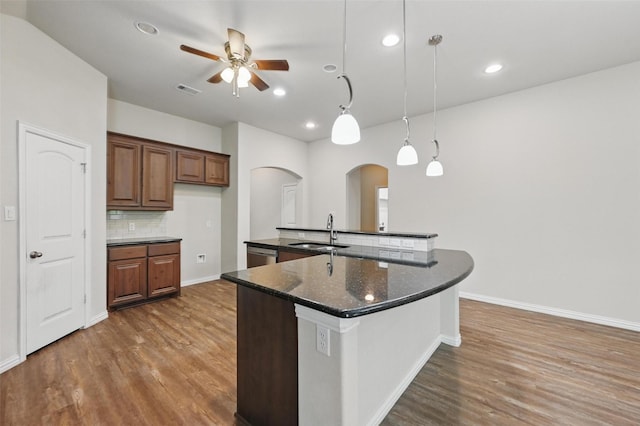 512 Hidden Springs Trl, Azle, TX 76020 - kitchen featuring arched walkways, a sink, ceiling fan, wood finished floors, and backsplash