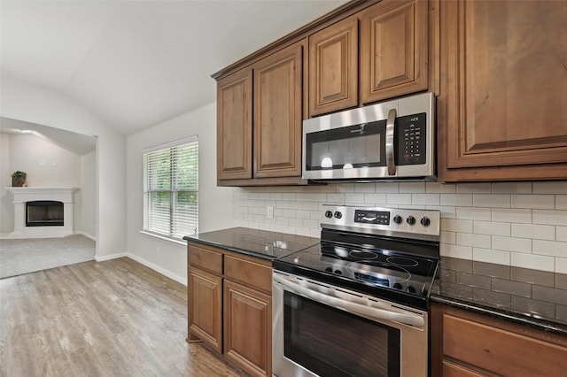 512 Hidden Springs Trl, Azle, TX 76020 - kitchen with stainless steel appliances, lofted ceiling, and brown cabinetry