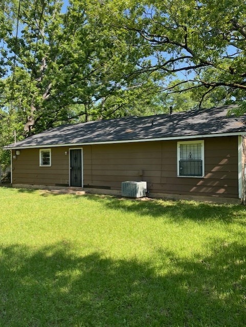 rear view of house with cooling unit and a yard