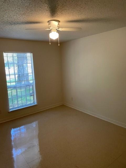 empty room with a textured ceiling, baseboards, and a ceiling fan