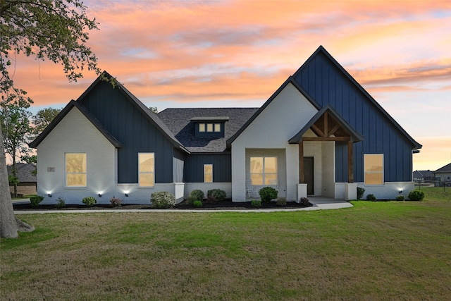 modern farmhouse featuring board and batten siding, a front yard, and brick siding