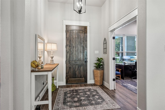 entrance foyer featuring baseboards, an inviting chandelier, and wood tiled floor