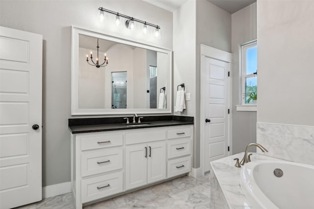 bathroom with a notable chandelier, marble finish floor, vanity, and a garden tub