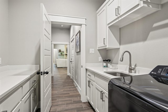 washroom featuring a sink, washer / clothes dryer, cabinet space, and dark wood finished floors