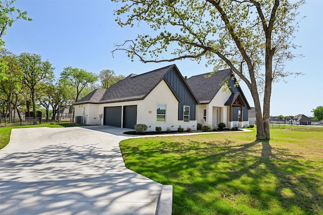view of front facade featuring a garage, board and batten siding, fence, a front lawn, and driveway
