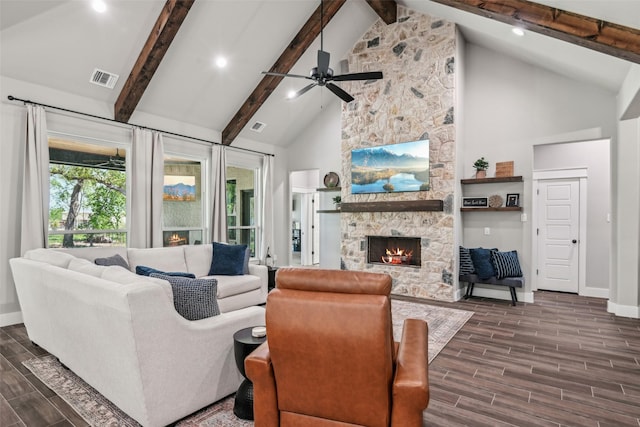 living area featuring visible vents, beamed ceiling, dark wood-style floors, and a stone fireplace