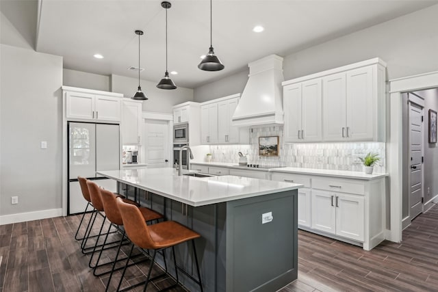 kitchen with custom range hood, stainless steel appliances, a sink, and dark wood finished floors