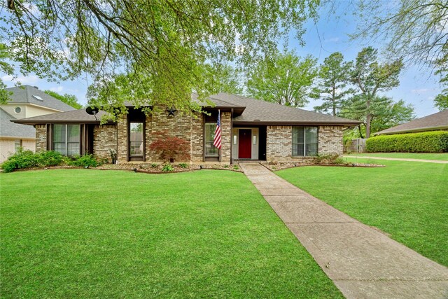 ranch-style home featuring a shingled roof, brick siding, and a front lawn