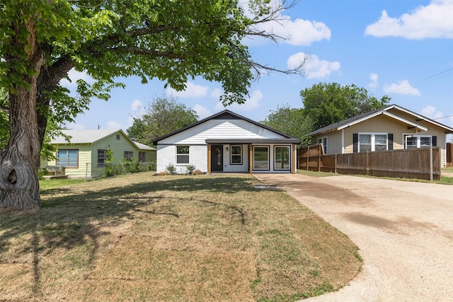 bungalow-style home with a front yard, fence, and concrete driveway