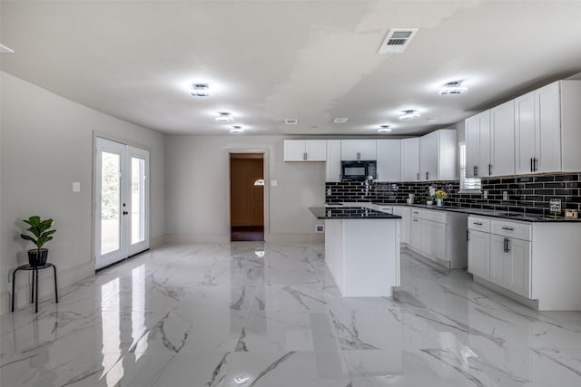 10061 Neosho Dr, Dallas, TX 75217 - kitchen with baseboards, dark countertops, black microwave, decorative backsplash, and a kitchen island