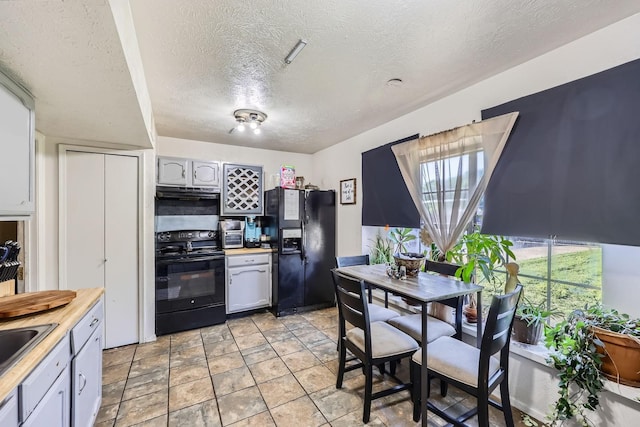kitchen with a sink, light countertops, a textured ceiling, under cabinet range hood, and black appliances