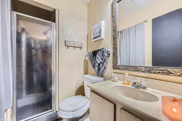 full bathroom with a textured wall, toilet, vanity, and a stall shower