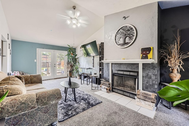 carpeted living area with a ceiling fan, vaulted ceiling, french doors, tile patterned floors, and a tile fireplace