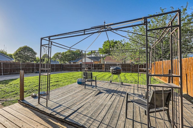 wooden terrace featuring grilling area, a fenced backyard, and a lawn
