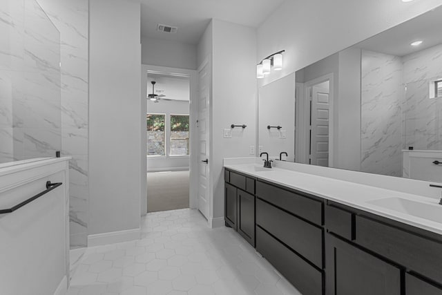 bathroom with a ceiling fan, visible vents, a sink, a marble finish shower, and double vanity