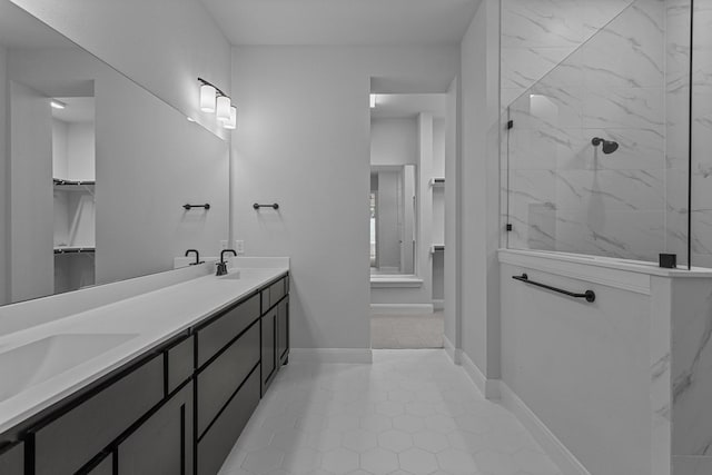 bathroom with tile patterned floors, a marble finish shower, a sink, and a spacious closet